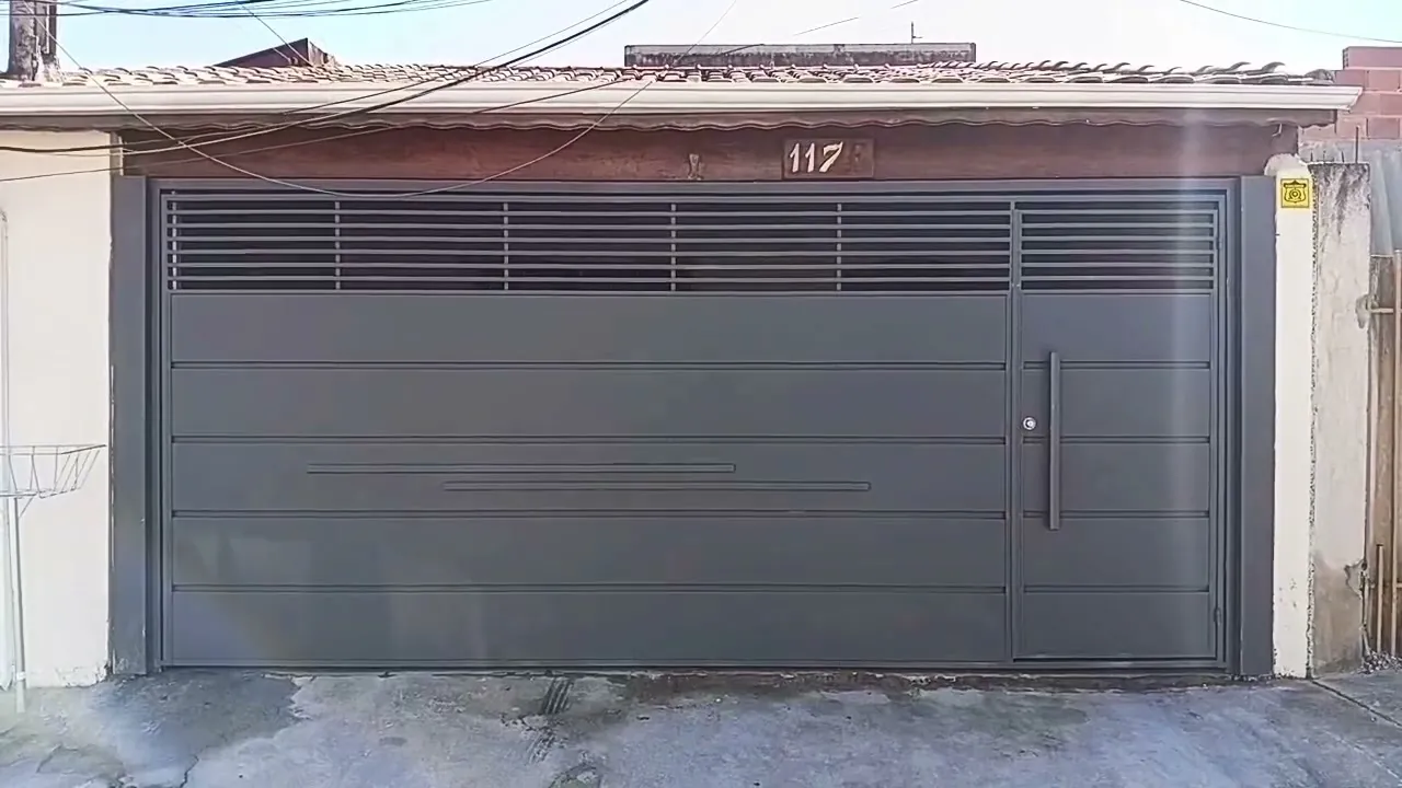 Portão de garagem largo em chapa cinza, com ventilação em cima